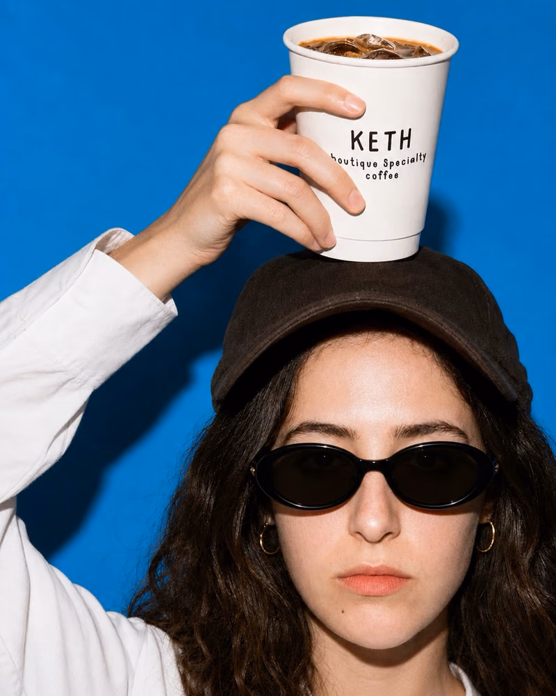 Hson content for Keth Coffee: an iced coffee balanced on a cap against a blue backdrop