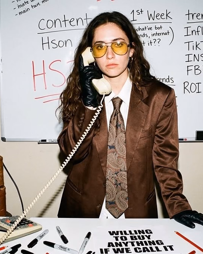 Hson campaign shot: model on a corded phone in front of a whiteboard of channel plans