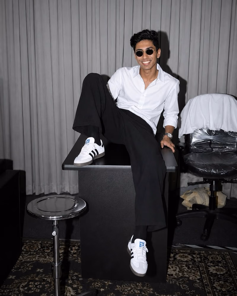 Hson campaign shot: model in a white shirt and trainers seated on a studio desk