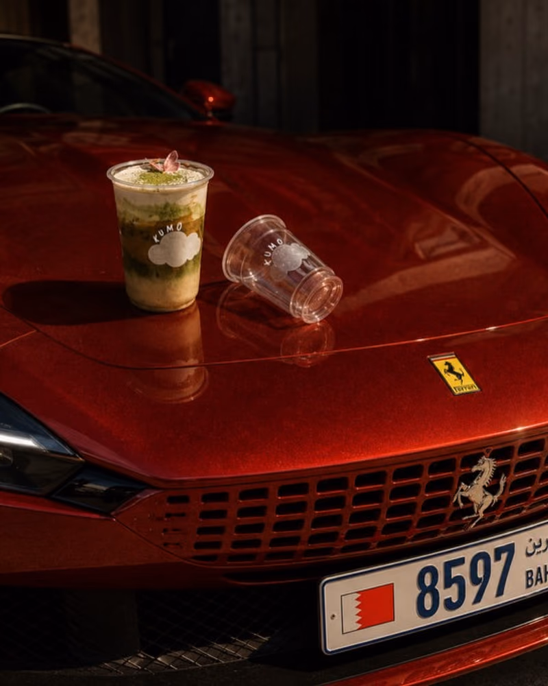 Hson content for Kumo: a matcha cup on the bonnet of a red sports car in Bahrain